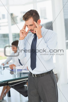 Thoughtful businessman with colleagues in meeting behind