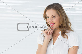 Smiling young businesswoman against blinds