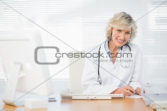 Smiling female doctor with computer at medical office