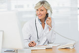 Female doctor with computer using phone at medical office