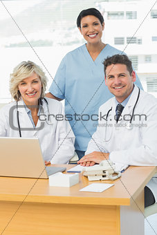 Smiling doctors with laptop at medical office