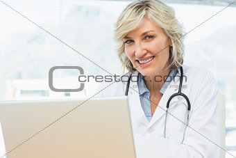 Smiling female doctor using laptop in medical office