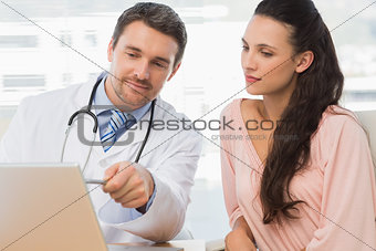 Male doctor showing something on laptop to patient