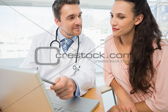 Doctor showing something on laptop to patient in medical office