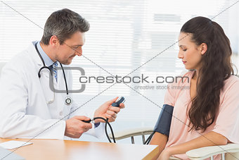 Male doctor checking blood pressure of a woman