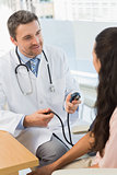 Male doctor checking blood pressure of a young woman