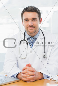 Male doctor with laptop at desk in medical office