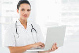 Portrait of a serious young female doctor using laptop
