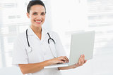 Portrait of a smiling female doctor using laptop