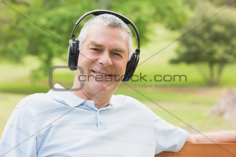 Smiling senior man with headphones at the park