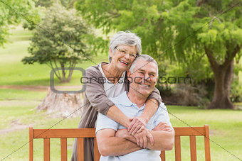 Senior woman embracing man from behind at park