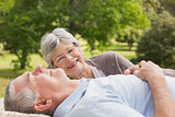 Side of a senior couple lying at park