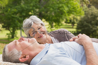 Side of a senior couple lying at park