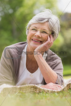 Smiling senior woman lying at park