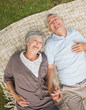 Smiling relaxed senior couple lying in park