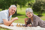 Happy senior couple playing chess at park