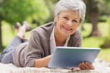 Smiling senior woman using digital tablet at park