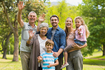 Extended family waving hands in park