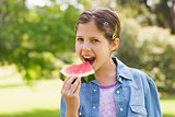 Smiling young girl eating water melon in park
