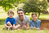 Smiling father with young kids lying on grass in park