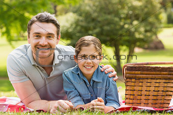 Smiling father with daughter lying on grass in park