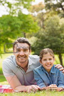Father with young daughter lying on grass in park