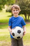 Smiling young boy holding ball in park