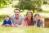 Smiling couple with young kids lying in park