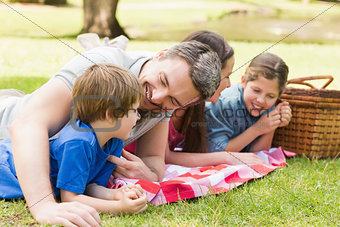 Smiling couple with young kids lying in park