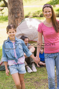 Mother and daughter with family behind in park