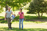 Family of three holding hands at park
