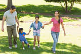 Family of four holding hands and walking at park
