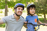 Smiling man with his son riding bicycle