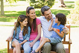 Couple with young kids sitting on park bench