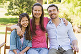 Smiling couple with daughter on park bench