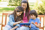 Woman with kids using digital tablet in park