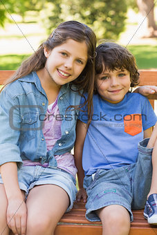 Young boy and girl sitting on park bench
