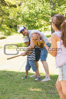 Family playing baseball in park