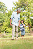 Grandfather and son walking on grass in park