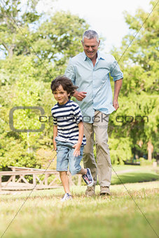 Grandfather and son running on grass in park