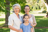 Smiling woman with grandmother and granddaughter at park