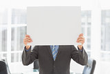 Businessman holding placard over his face
