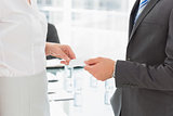 Businessman handing businesswoman a card