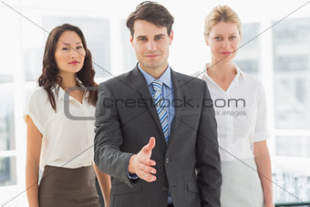 Happy businessman reaching hand out in front of his team