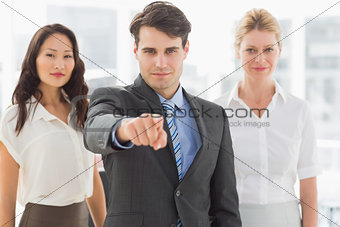 Happy businessman pointing to camera in front of his team