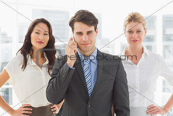 Smiling businessman on the phone in front of his team