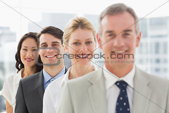 Cheerful business team standing in a line smiling at camera