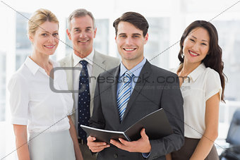 Businessman holding document smiling at camera with his team