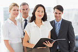 Businesswoman holding document smiling at camera with her team