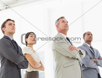 Serious business team with arms crossed looking up